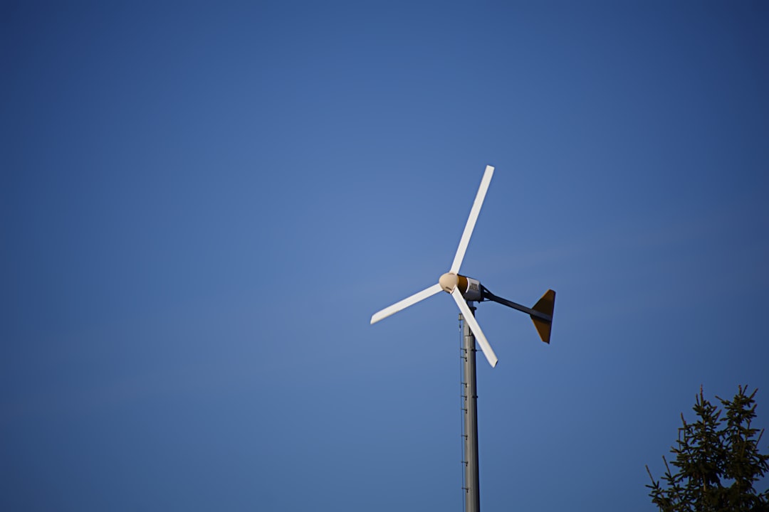a-wind-turbine-spins-against-a-blue-sky-yxd6bnzptii